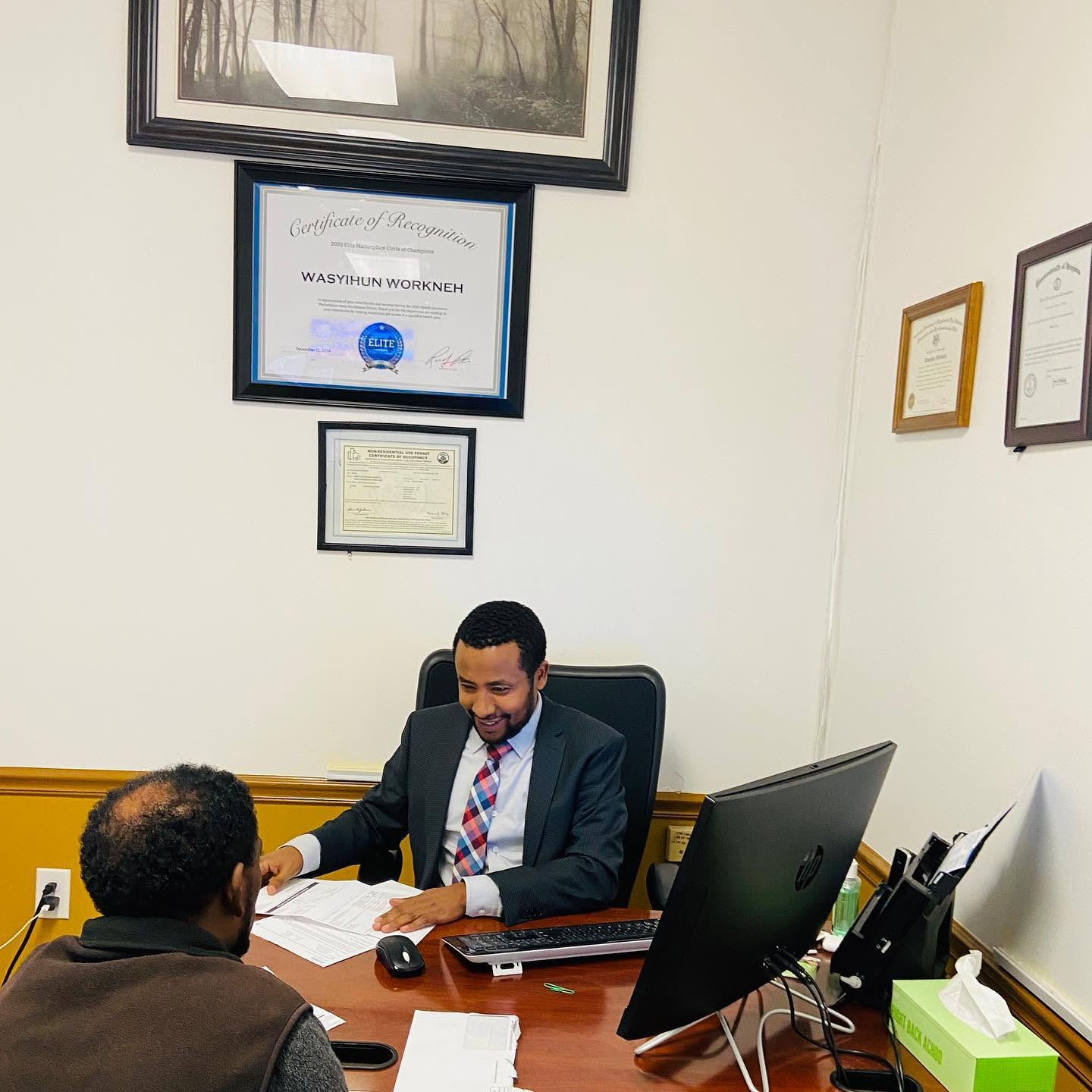 Wasyihun Workneh helping a client at his desk in the Brook Tax and Insurance office